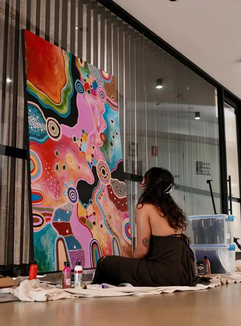 Photo of Emma in front of her artwork